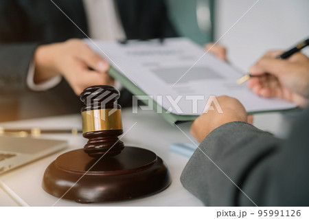 Close up view of auction hammer on the desk in Legal counsel presents to the client a signed contract as courtroom. 95991126