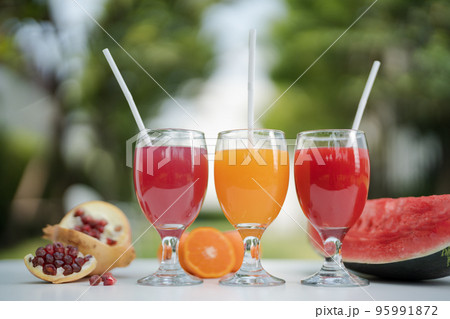 Orange juice, pomegranate juice and watermelon juice on the natural background Orange juice, pomegranate juice and watermelon juice on the natural background 95991872