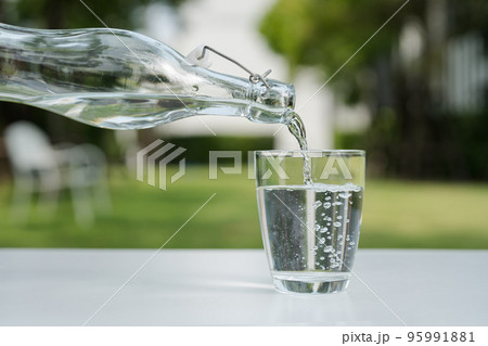 Pour the water from the water bottle into the glass. 95991881
