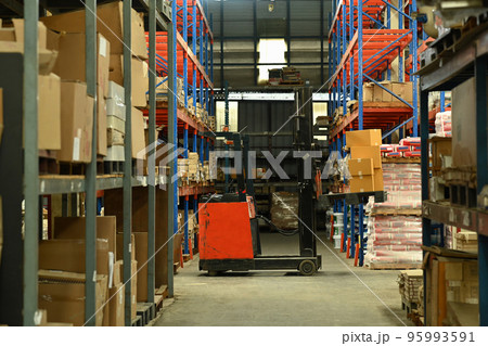 Forklift truck in large logistic distribution warehouse full of shelves with cardboard boxes 95993591