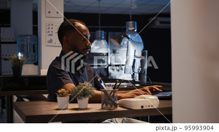 Office worker analyzing startup data on laptop to create project, using research to plan executive presentation. Working at night to do company sales sharing and send email. 95993904