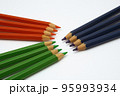 Wooden crayons arranged according to color and facing each other with their tips 95993934