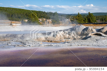 Idyllic view of Avoca spring with blue sky in background. Geothermal landscape at Biscuit basin in famous Yellowstone National park. Tourist attraction in forest during summer. Idyllic view of Avoca spring with blue sky in background. Geothermal landscape at Biscuit basin in famous Yellowstone National park. Tourist attraction in forest during summer. 95994154