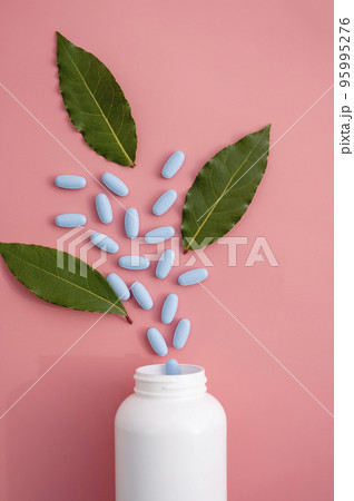 Natural food supplements pills, white plastic bottle with vitamins, pink background and sun light with shadows. 95995276