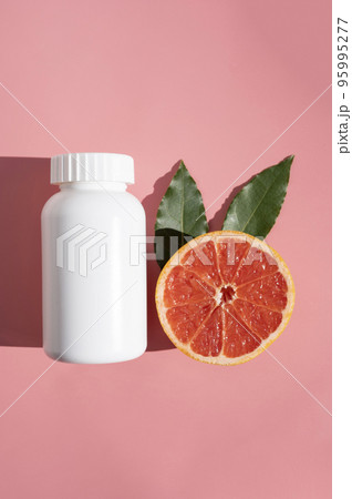 Natural food supplements pills, white plastic bottle with vitamins, pink background and sun light with shadows. Natural food supplements pills, white plastic bottle with vitamins, pink background and sun light with shadows. 95995277