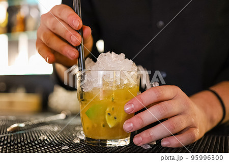 Barman is making cocktail at night club in a classic cocktail glasses. Barman is making cocktail at night club in a classic cocktail glasses. 95996300