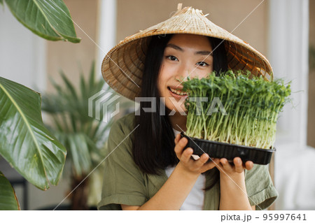 Portrait of young asian woman holding microgreen sprouts on tropical exotic background Portrait of young asian woman holding microgreen sprouts on tropical exotic background 95997641