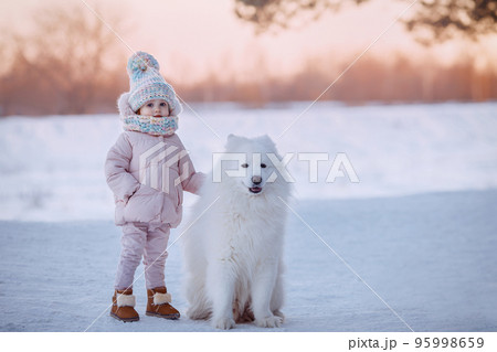 Charming little girl in a warm coat with a dog Charming little girl in a warm coat with a dog 95998659
