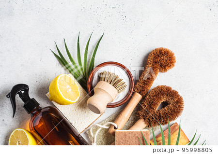 Zero waste eco friendly products and tools for house cleaning. Wooden brushes, coconut sponges, spray vinegar, soda, lemon and organic soap, gray background. 95998805