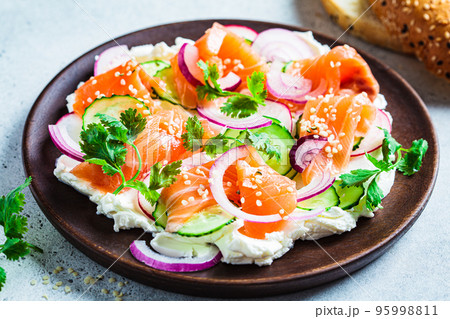 Butter board with salted salmon, cucumber, radish and cilantro on wooden plate. Party snack food, cooking trend. Butter board with salted salmon, cucumber, radish and cilantro on wooden plate. Party snack food, cooking trend. 95998811
