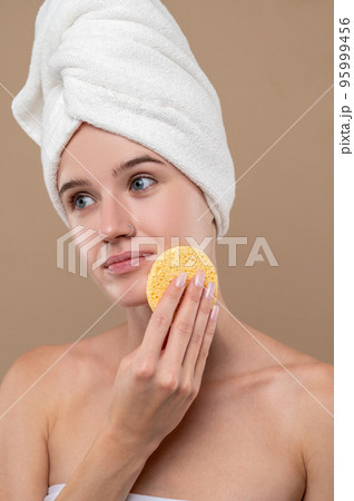 Pretty young girl cleaning her face with a sponge Pretty young girl cleaning her face with a sponge 95999456