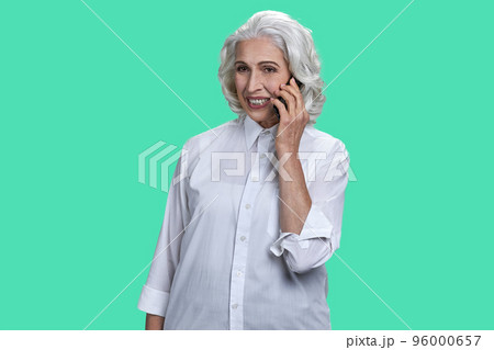 Portrait of aged old woman talking on phone. Isolated over pastel green background. 96000657