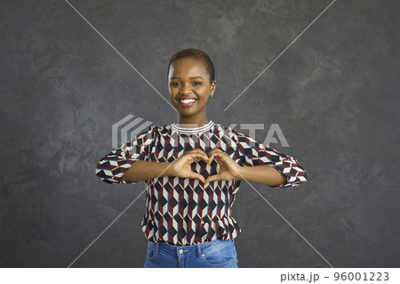 Portrait of a young African American woman forming a heart symbol with her hands 96001223