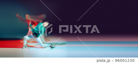 Portrait of young man and woman dancing isolated over green purple background in neon with mixed lights. Flyer 96001230
