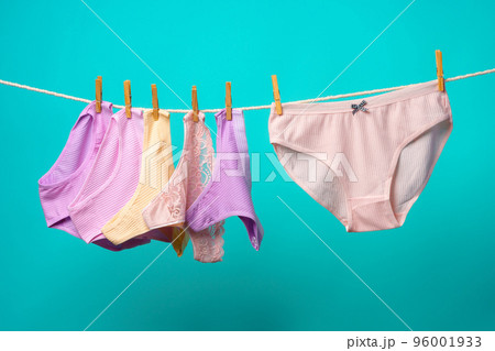 Female panties hanging on rope against blue studio background 96001933