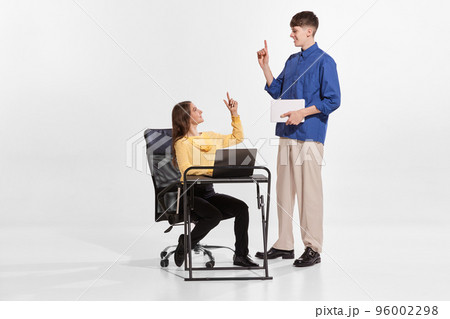 Portrait of two people, employees, man and woman helping each other, giving advice isolated over white background 96002298