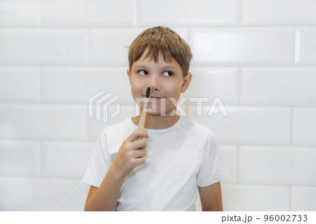cute 8 years old boy brushing teeth with bamboo tooth brush with black bristles in bathroom. cute 8 years old boy brushing teeth with bamboo tooth brush with black bristles in bathroom. 96002733