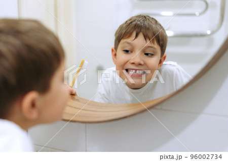 cute 8 years old boy washing face in bathroom looking in mirror and smiling. cute 8 years old boy washing face in bathroom looking in mirror and smiling. 96002734