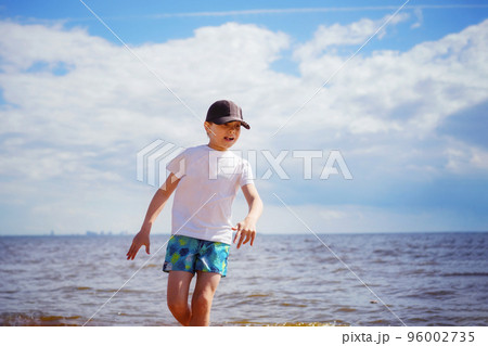Happy little boy is running in the sea on sunny summer day. Childhood concept Happy little boy is running in the sea on sunny summer day. Childhood concept 96002735