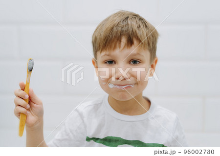 cute 5 years old boy brushing teeth with bamboo tooth brush in bathroom. Image with selective focus cute 5 years old boy brushing teeth with bamboo tooth brush in bathroom. Image with selective focus 96002780