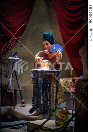 Portrait of magnificent fortune teller woman reading future on magical crystal ball and tarot cards. Concept of vintage style, retro circus, art, fate 96004268