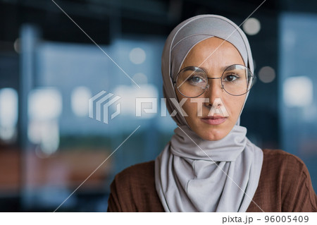 Closeup photo portrait of successful thinking business woman wearing hijab and glasses, woman looking at camera working inside modern office building. 96005409