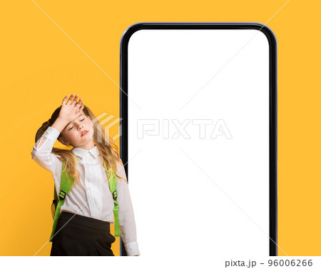 Tired Preteen Schoolgirl Standing Near Big Smartphone With Blank Screen 96006266
