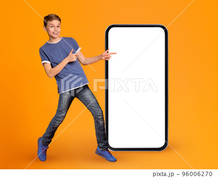 Great App. Joyful Male Kid Pointing At Smartphone With Blank White Screen Great App. Joyful Male Kid Pointing At Smartphone With Blank White Screen 96006270