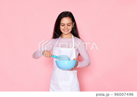 woman holding whisk and bowl with eggs 96007496