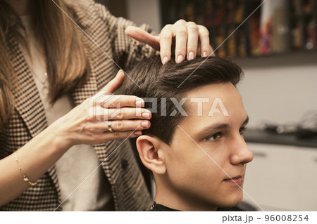 Young man getting a modern haircut. Hair salon master does hair styling client at barber shop. Men's 96008254