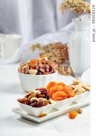 Dried fruits and assorted nuts on a white table. Dried fruits and assorted nuts on a white table. 96008326