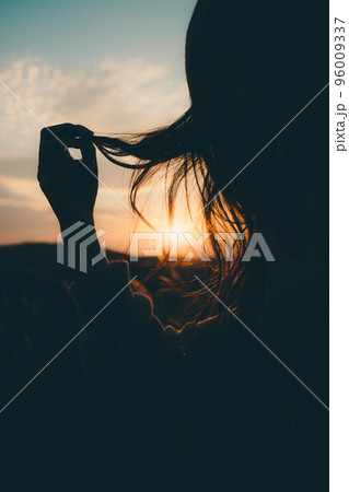 夕暮れの自然の中に佇む女性のシルエット写真 96009337