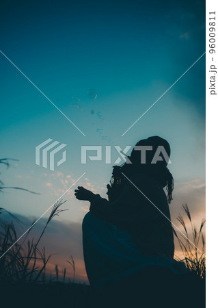 夕暮れの自然の中で佇む女性のシルエット写真 96009811
