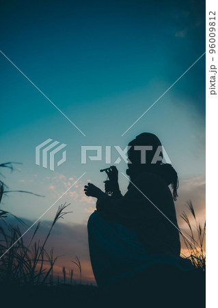 夕暮れの自然の中で佇む女性のシルエット写真 96009812