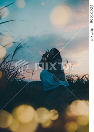 夕暮れの自然の中で佇む女性のシルエット写真 96010024