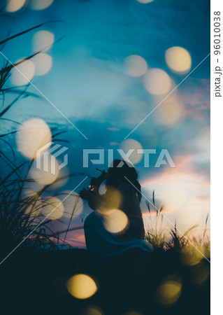 夕暮れの自然の中で佇む女性のシルエット写真 96010038