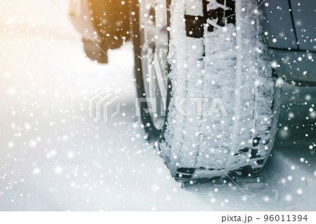 Close up detail car wheel with new black rubber tire protector on winter snow covered road. Transportation and safety concept. Close up detail car wheel with new black rubber tire protector on winter snow covered road. Transportation and safety concept. 96011394