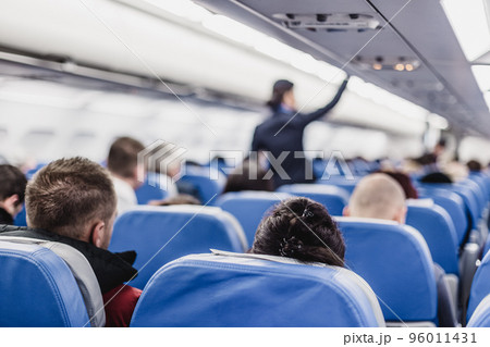 Interior of airplane with passengers on seats and stewardess walking the aisle. 96011431