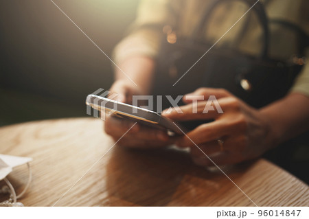 Close-up of woman's hand using a smartphone during coffee break. Close-up of woman's hand using a smartphone during coffee break. 96014847