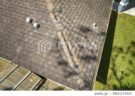 Wind damaged house roof with missing asphalt shingles after hurricane Ian in Florida. Repair of home rooftop concept 96015403