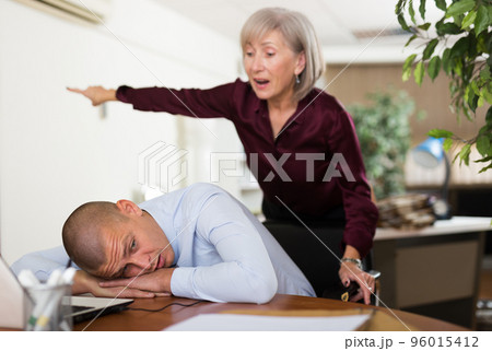 Office worker sleeping on table and chief shouting at him Office worker sleeping on table and chief shouting at him 96015412