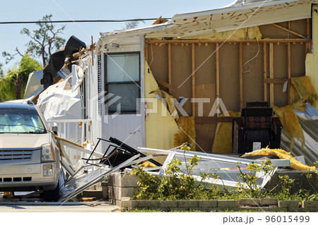 Severely damaged house and car after hurricane Ian in Florida mobile home residential area. Consequences of natural disaster 96015499