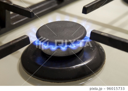 Burning gas stove hob blue flames close up in the dark on a black background Burning gas stove hob blue flames close up in the dark on a black background 96015733