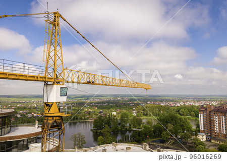 Apartment or office tall building under construction. Brick walls, glass windows, scaffolding and concrete support pillars. Tower crane on bright blue sky copy space background. 96016269