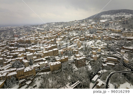 Aerial winter landscape of dense historic center of Thiers town in Puy-de-Dome department, Auvergne-Rhone-Alpes region in France. Rooftops of old buildings and narrow streets at snowfall 96016299