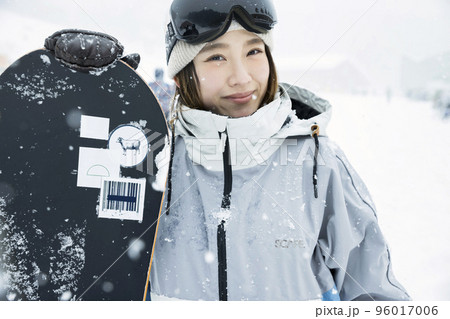 雪の降るスキー場で笑顔で立つスノボ女子 96017006