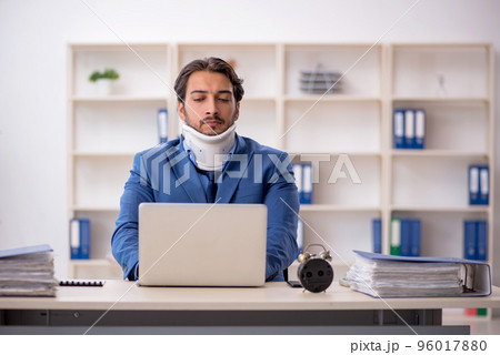 Young male employee after accident sitting at workplace 96017880