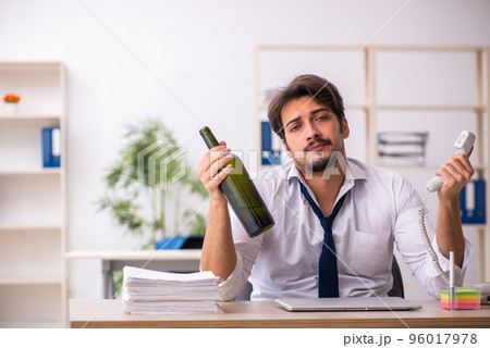 Young alcohol addicted employee sitting in the office 96017978