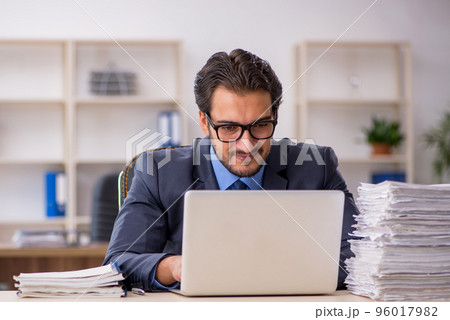 Young male employee and too much work in the office 96017982