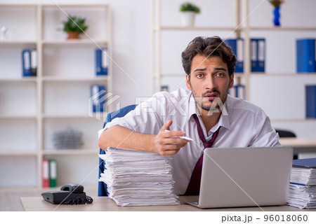 Young male employee and too much work in the office 96018060